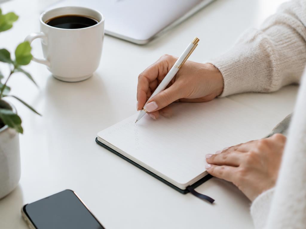 Mãos escrevendo objetivos em um caderno